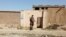 FILE - A Taliban fighter stands guard in front of a house adjacent to a suspected Islamic State hideout raided by Taliban forces, in northern Kabul, Afghanistan, Oct. 4, 2021.