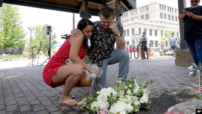 Brooke y Matt Strauss, que se casaron el domingo, hacen una pausa después de dejar sus ramos de novia en el centro de Highland Park, Illinois, un suburbio de Chicago, cerca del lugar del tiroteo masivo del lunes 5 de julio de 2022.