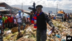 FILE - Barbecue, the leader of the "G9 and Family" gang, stands next to garbage to call attention to the conditions people live in as he leads a march against kidnapping through the La Saline neighborhood in Port-au-Prince, Haiti, Oct. 22, 2021.