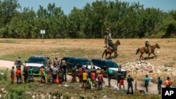 FILE - U.S. Border Patrol officers contain a group of migrants on the shore of the Rio Grande after they crossed from Ciudad Acuña, Mexico, into Del Rio, Texas, Sept. 19, 2021.