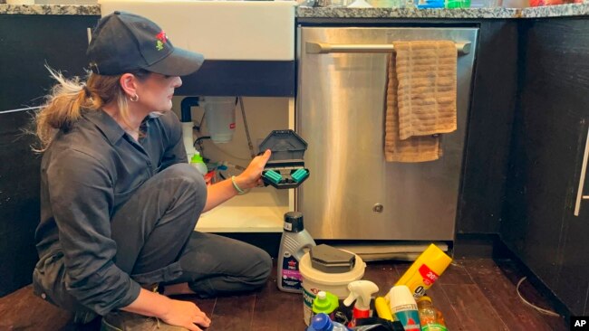 Ava Dickman, a technician with AAA Exterminating Inc., checks a rodent bait station inside a home in Indianapolis, May 16, 2022.