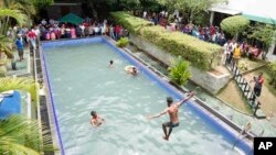 Protesters swim as onlookers wait at a swimming pool in president's official residence a day after it was stormed in Colombo, July 10, 2022.