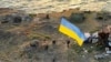 In this photo provided by the Ukrainian Defense Ministry Press Office July 7, 2022, Ukrainian soldiers hoist the national flag on Snake island, in the Black Sea. The outpost had been under the control of Russian troops for much of the war.