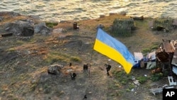 En esta foto proporcionada por la Oficina de Prensa del Ministerio de Defensa de Ucrania el 7 de julio de 2022, los soldados ucranianos instalan la bandera nacional en la isla Snake, en el Mar Negro. El puesto de avanzada había estado bajo el control de las tropas rusas.