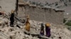 Afghan women carry water containers through the debris of damaged houses after the recent earthquake in Wor Kali village, June 25th, 2022.