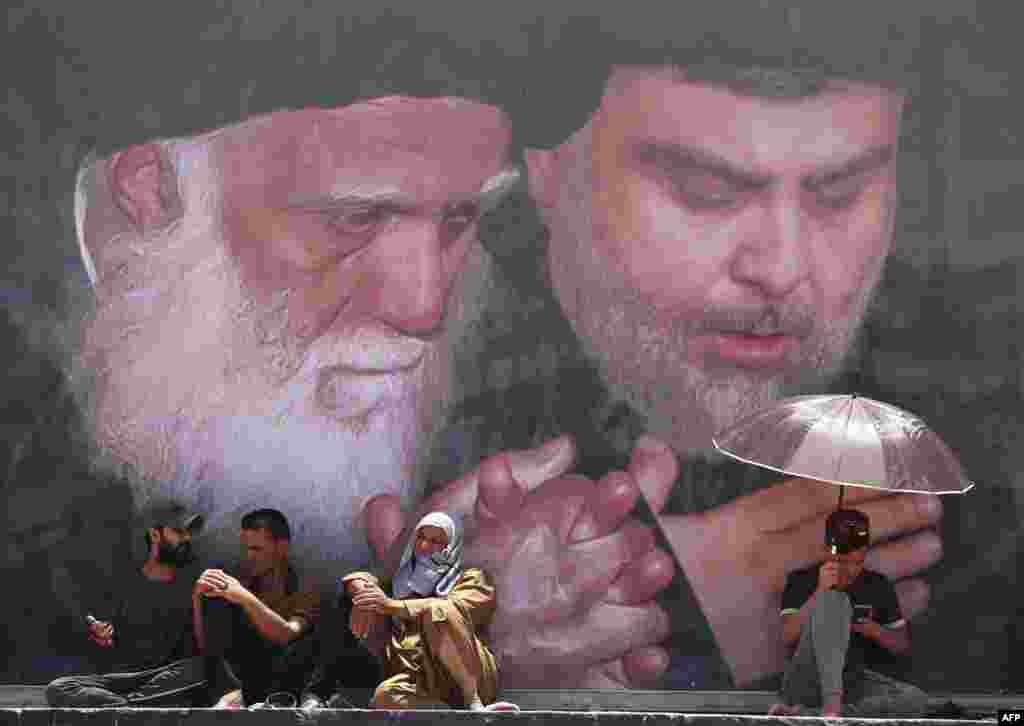 Supporters of Iraqi Shiite cleric Muqtada al-Sadr, portrait at right, attend Friday prayers in Sadr City, east of the capital Baghdad, Iraq.