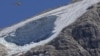 A rescue helicopter hoovers over the Punta Rocca glacier near Canazei, in the Italian Alps in northern Italy, Monday, July 4, 2022