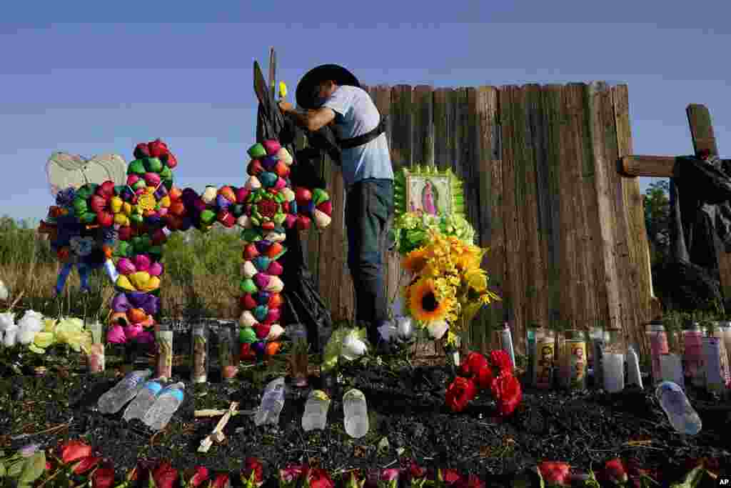 Roberto Marquez of Dallas adds a flower to a makeshift memorial at the site where officials found dozens of people dead in an abandoned semitrailer containing suspected migrants, in San Antonio, Texas.