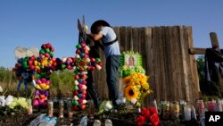 Roberto Marquez of Dallas adds a flower to a makeshift memorial at the site where officials found dozens of people dead in an abandoned semitrailer containing suspected migrants, in San Antonio, Texas.