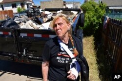 FILE - Pam Smith is seen in front of a trailer filled with her belongings that were ruined in flooding, in Red Lodge, Mont., on June 16, 2022.