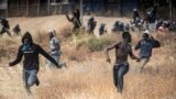 FILE: Migrants run on Spanish soil after crossing the fences separating the Spanish enclave of Melilla from Morocco in Melilla, Spain, June 24, 2022.