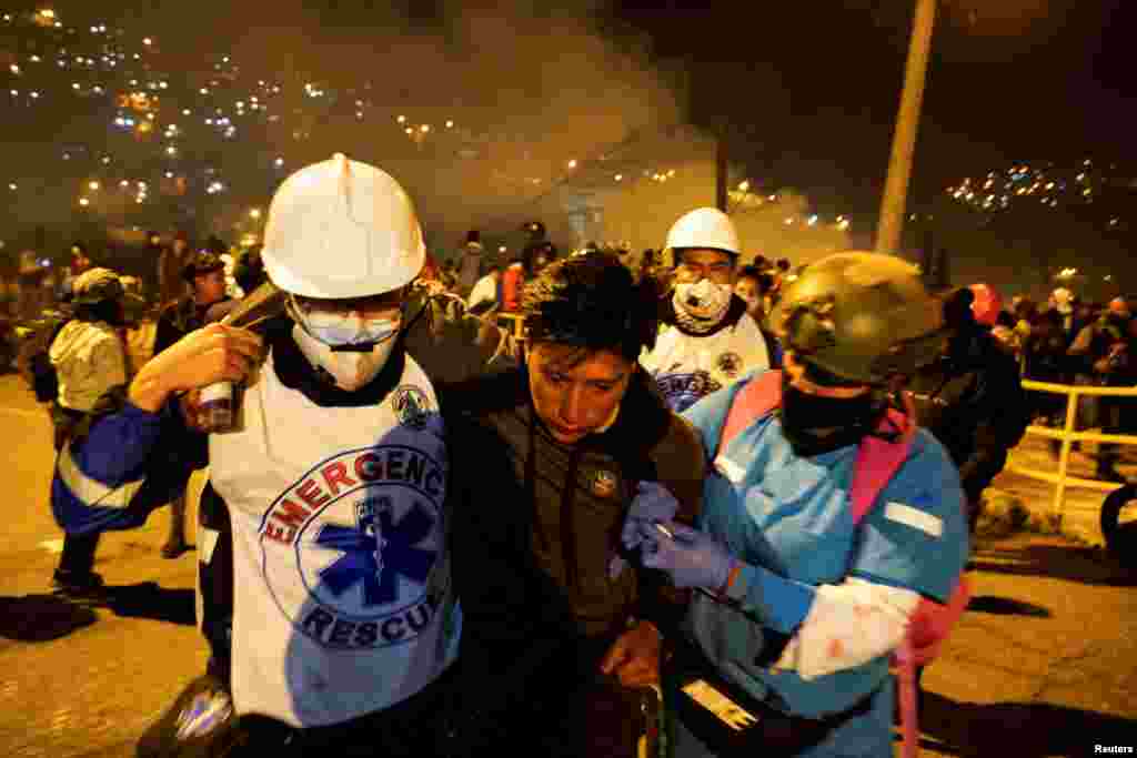 Un hombre es auxiliado por personal médico de emergencia tras ser afectado por gases lacrimógenos disparados por las fuerzas de seguridad.&nbsp;