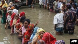 সুনামগঞ্জে ভারী বৃষ্টির পর বন্যায় ক্ষতিগ্রস্ত মানুষ ত্রাণ সংগ্রহের জন্য হাঁটু-গভীর পানিতে সারিবদ্ধভাবে অপেক্ষা করছেন। ২১ জুন ২০২২। (ছবি-মোঃ আবু সুফিয়ান জুয়েল / এএফপি)