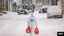 A police officer wearing personal protective equipment carries food that will be distributed to residents at a restricted area due to the spread of the Covid-19 coronavirus in Manzhouli, China.