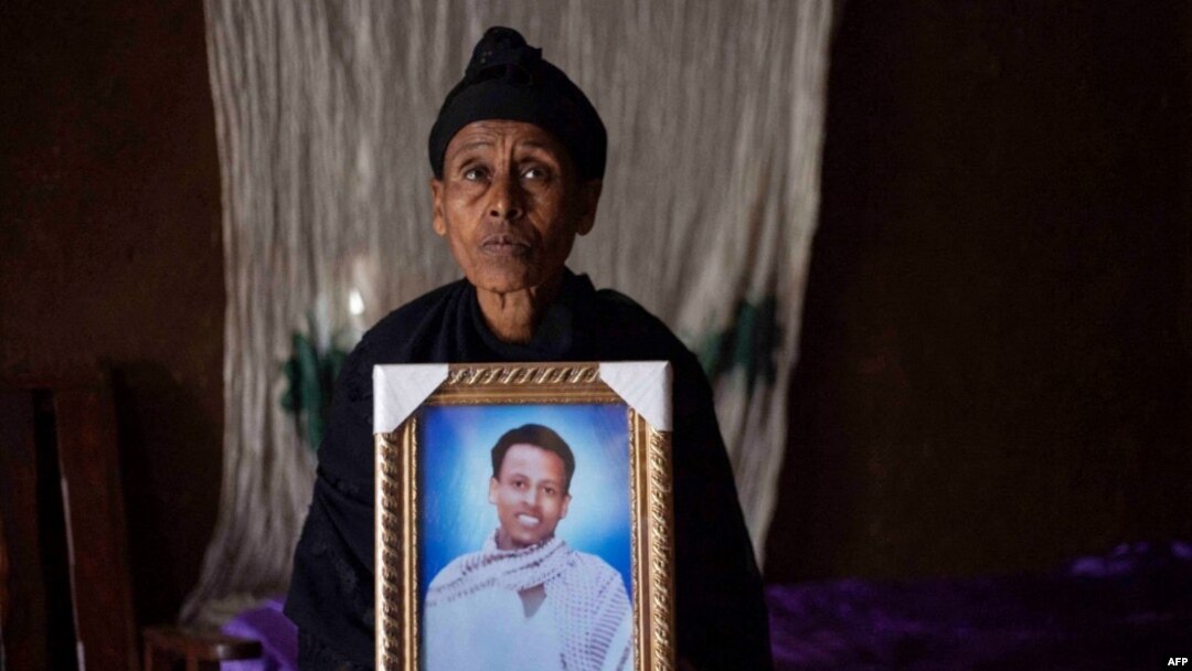 FILE - Likitu Merdasa holds a portrait of her son Desta Garuma, a 27-year-old rickshaw driver, allegedly killed by security forces, at her home in Nekemte, West Oromia, Ethiopia, Feb. 26, 2020.