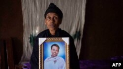FILE - Likitu Merdasa holds a portrait of her son Desta Garuma, a 27-year-old rickshaw driver, allegedly killed by security forces, at her home in Nekemte, West Oromia, Ethiopia, Feb. 26, 2020.