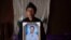 FILE - Likitu Merdasa holds a portrait of her son Desta Garuma, a 27-year-old rickshaw driver, allegedly killed by security forces, at her home in Nekemte, West Oromia, Ethiopia, Feb. 26, 2020.