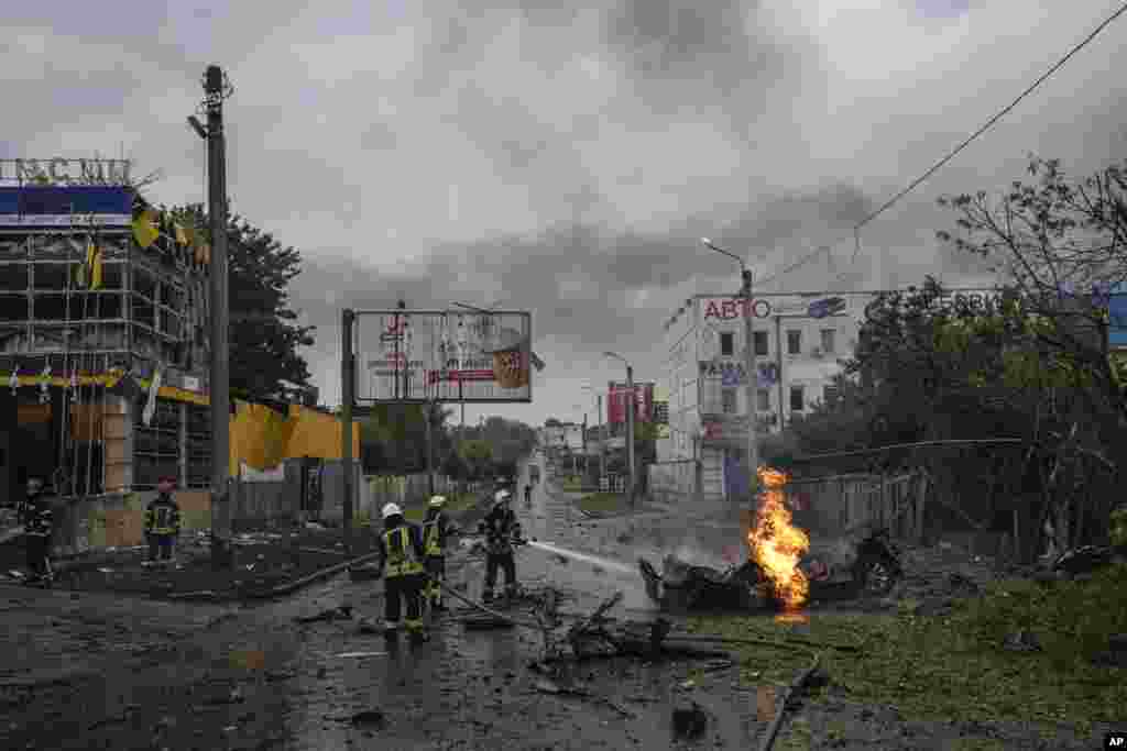 Rescue workers put out the fire of a destroyed car after a Russian attack in a residential neighborhood in downtown Kharkiv, Ukraine.