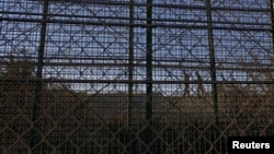 FILE - Moroccan soldiers walk on the Moroccan side of a border fence with Spain's north African enclave of Melilla, in this picture taken on the Spanish side of the fence, Dec. 12, 2014.