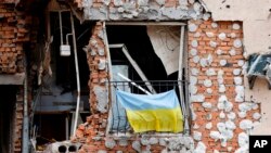 A Ukrainian national flag hangs from a balcony of a civilian destroyed building in Irpin, outside Kyiv, June 16, 2022.