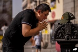 FILE - A man cools off in a fountain during a hot day in downtown Madrid, Spain, June 18, 2022.