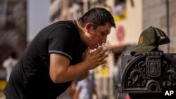 Seorang pria tampak mencoba mendinginkan dirinya dengan bantuan air mancur di pusat Kota Madrid, Spanyol, pada 18 Juni 2022. (Foto: AP/Manu Fernandez)