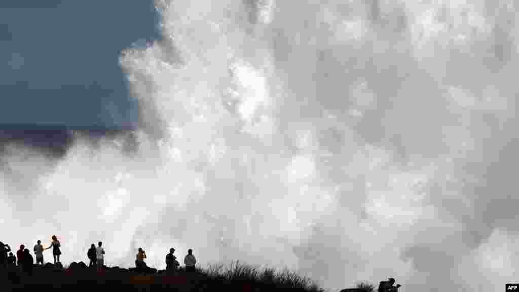 People watch the waves during a breaking swell in Saint-Leu, in the south of the French island of Reunion, Indian Ocean, after a wave-submergence alert was declared.