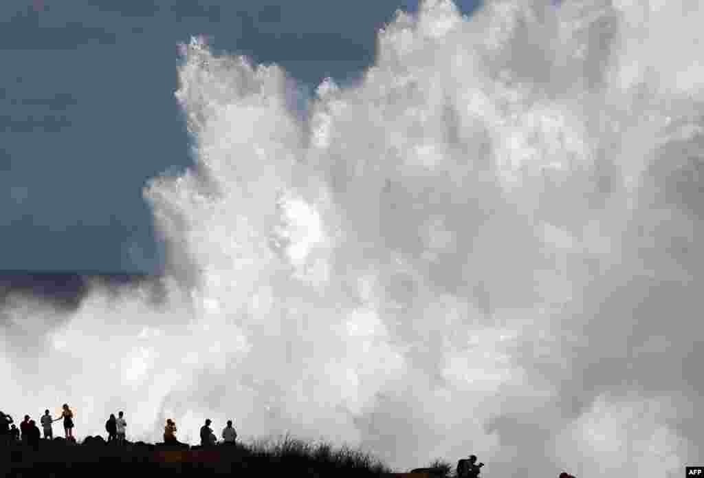 Residents watch the waves during a breaking swell in Saint-Leu, in the south of the French island of Reunion, Indian Ocean, after a wave-submergence alert was declared.