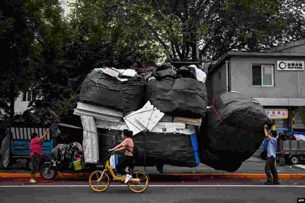 Workers load a large sack of foam on a tricycle in front of a waste sorting area in Beijing, China.