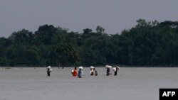 ত্রাণ সামগ্রী সংগ্রহ করার পর কোম্পানীগঞ্জে লোকেরা প্লাবিত এলাকা দিয়ে হেঁটে যাচ্ছে। (ছবি-এএফপি)