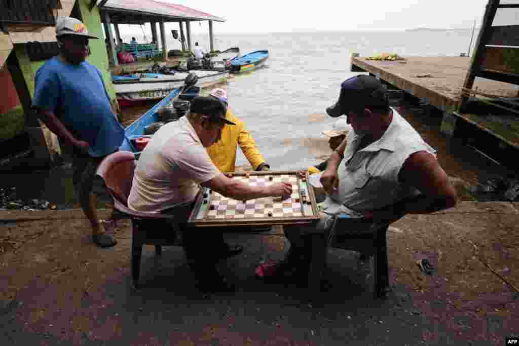 Pescadores juegan tablero en el puerto antes de la llegada de la tormenta tropical Bonnie, en Bluefields, Nicaragua, el 30 de junio de 2022.