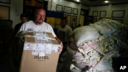 A volunteer carry boxes of goods to a van to be delivered to soldiers fighting on the eastern and southern fronts, dispatched from an NGO storage center in Kyiv, Ukraine, Monday, June 13, 2022. (AP Photo/Natacha Pisarenko)