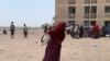 A displaced woman walks away with a food bag at the Dubti displaced peoples site in Northern Ethiopia. (Halima Athumani/VOA)
