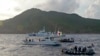 FILE - Japanese Coast Guard vessel and boats, rear and right, sail alongside a Japanese activists' fishing boat, center with a flag, near a group of disputed islands called Diaoyu by China and Senkaku by Japan, Aug. 18, 2013.