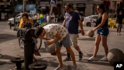 Seorang pria menyejukkan diri di air mancur di pusat kota Madrid, Spanyol, Sabtu, 18 Juni 2022. (Foto: AP)