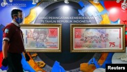 Ilustrasi - Seorang pria yang mengenakan masker berjalan melewati gambar uang kertas tujuh puluh lima ribu rupiah ysng dipajang di dinding kantor pusat Bank Indonesia di Jakarta, 2 September 2020. (REUTERS/Ajeng Dinar Ulfiana)