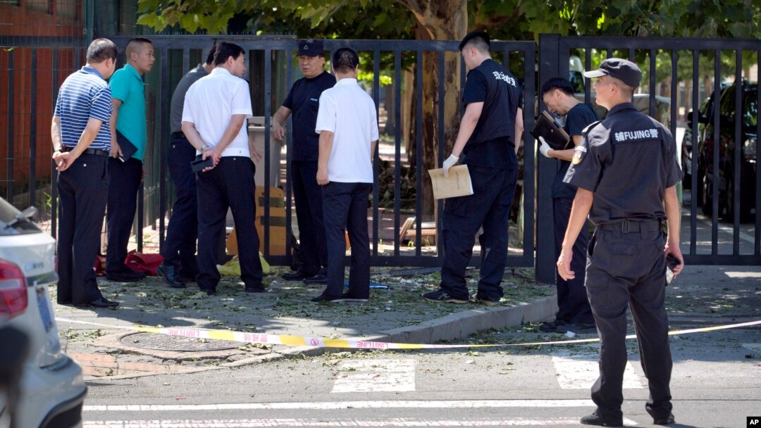 Zvaničnici i bezbednosno osoblje stoje u blizni mesta eksplozije ispred južnog dela Ambasade SAD u Pekingu, 26. jula 2018. July 26, 2018.