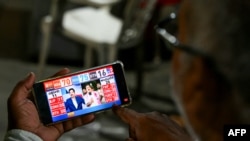 A man watches exit polls on his mobile phone after voting concluded at the end of the seventh and final phase of voting in India's general election, in Hyderabad on June 1, 2024.