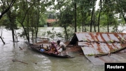 Warga menaiki perahu untuk pergi menuju tempat pengungsian di tengah banjir yang melanda kawasan timur laut Bangladesh di Kota Sylhet, pada 19 Juni 2022. (Foto: Reuters/Kazi Salahuddin Razu)