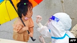 中国安徽省泗县的医护人员在给一名女童做新冠核酸检测。（2022年7月4日）