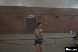 A woman stands in front of a market after it was shelled, as Russia’s attack on Ukraine continues, in Sloviansk, Donetsk province, July 5, 2022.