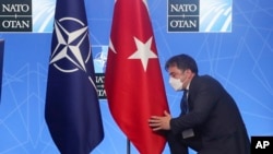 FILE - An official adjusts the Turkish flag prior to a media conference of Turkey's President Recep Tayyip Erdogan at a NATO summit in Brussels, June 14, 2021.