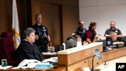 El juez del condado de Lake, Theodore Potkonjak, a la izquierda, mira una pantalla de video mientras preside la comparecencia inicial de Robert E. Crimo III en el juzgado del condado, el 6 de julio de 2022, en Waukegan, Illinois.