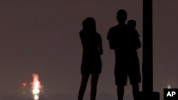 FILE - People watch distant holiday fireworks, July 3, 2020, from a park in Kansas City, Mo. Two men have been charged with murder in a house explosion near St. Louis that authorities say killed four people who were assembling unlicensed fireworks in a garage.
