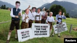 FILE: Activists of the NGO ONE, wearing masks depicting G-7 leaders, protest the G-7 summit to be held in the nearby Bavarian alpine resort hotel Elmau Castle, in Garmisch-Partenkirchen, Germany.