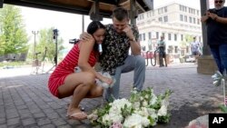 Brooke y Matt Strauss, que se casaron el domingo, hacen una pausa el martes 5 de julio de 2022 después de dejar sus ramos de boda en el centro de Highland Park, Illinois, un suburbio de Chicago, cerca de la escena de la masacre del lunes. (AP Foto/Charles Rex Arbogast)