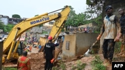 Les sauveteurs utilisent de la machinerie lourde pour rechercher des survivants après l'effondrement de maisons, le 16 juin 2022 à Abidjan.