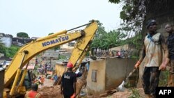Les sauveteurs utilisent de la machinerie lourde pour rechercher des survivants après l'effondrement de maisons, le 16 juin 2022, dans le district d'Attecoube à la suite de fortes pluies à Abidjan.
