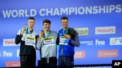 From left to right, Florian Wellbrock of Germany, Bobby Finke of the United States, and Mykhailo Romanchuk of Ukraine pose with their medals after the Men 800m Freestyle final.at the 19th FINA World Championships in Budapest, Hungary on June 21, 2022.