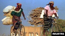 FILE: In this undated photo, women in Burkina Faso carry wood and sacks of food on bicycles, a major form of transport in the dusty and poor West Africa. 